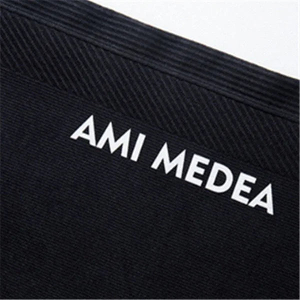 Close-up of black fabric waistband with AMI MEDEA text in white letters